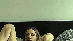 A beautiful skinny blonde lies on her soft bed, gently masturbating her cute pussy all alone