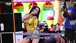 Two pretty indonesian singers perform a wild dance on stage surrounded by men