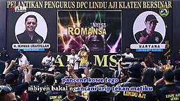 Two pretty indonesian singers perform a wild dance on stage surrounded by men